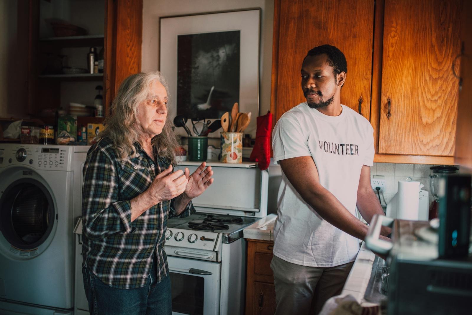 Two volunteers connect over cooking, fostering community spirit in a cozy kitchen setting.